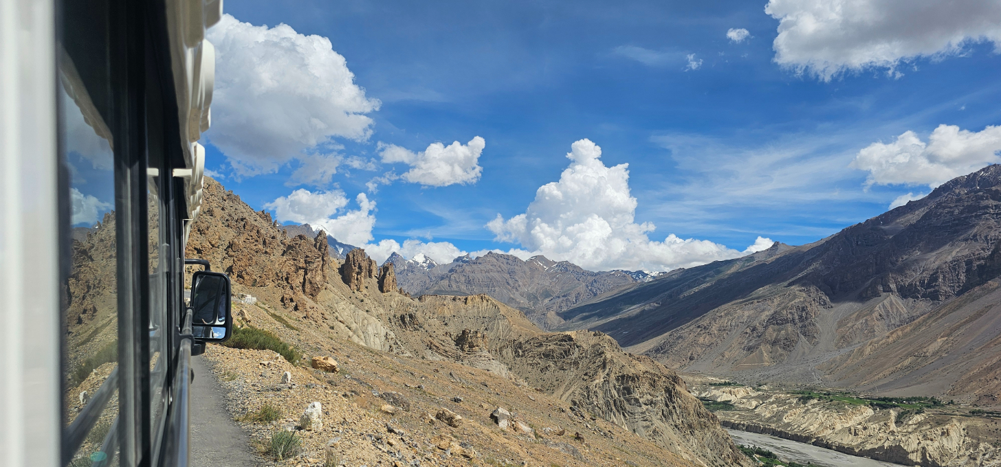 View from a bus window showing winding mountain roads and a valley