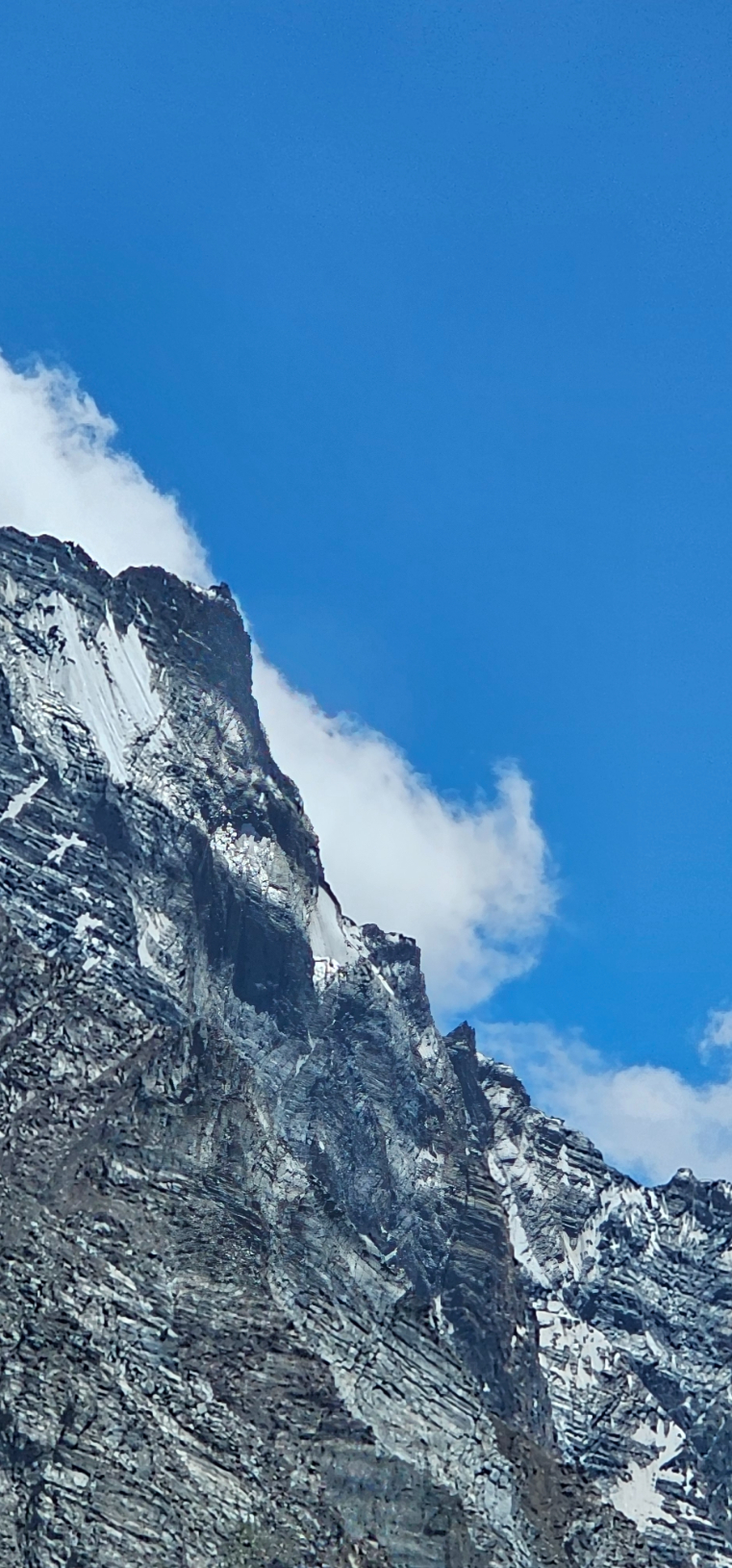 A close-up view of a rugged, snowy mountain peak against a blue sky