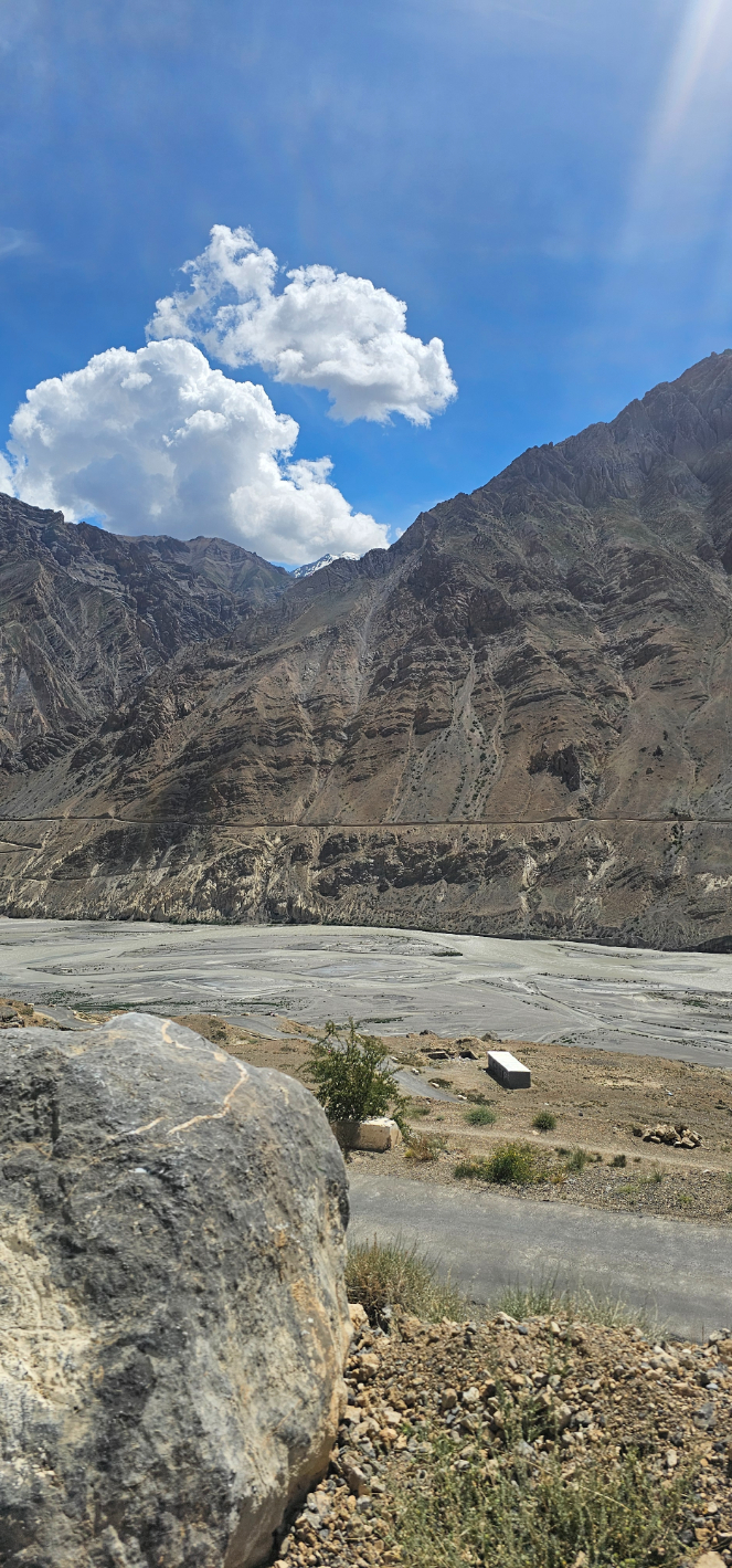 Wide shot of rugged mountains and a dry river bed under a blue sky