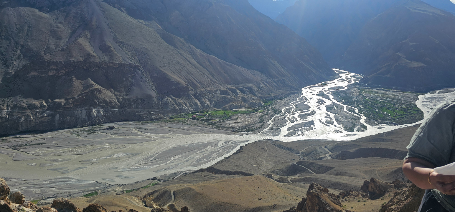 A wide river flowing through a vast, arid valley with distant mountains